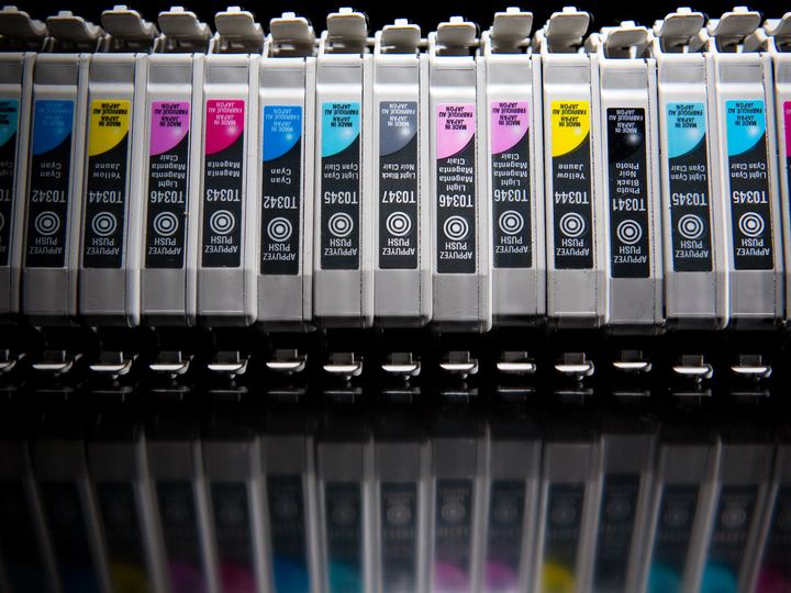 A pile of used inkjet printer cartridges in several colors